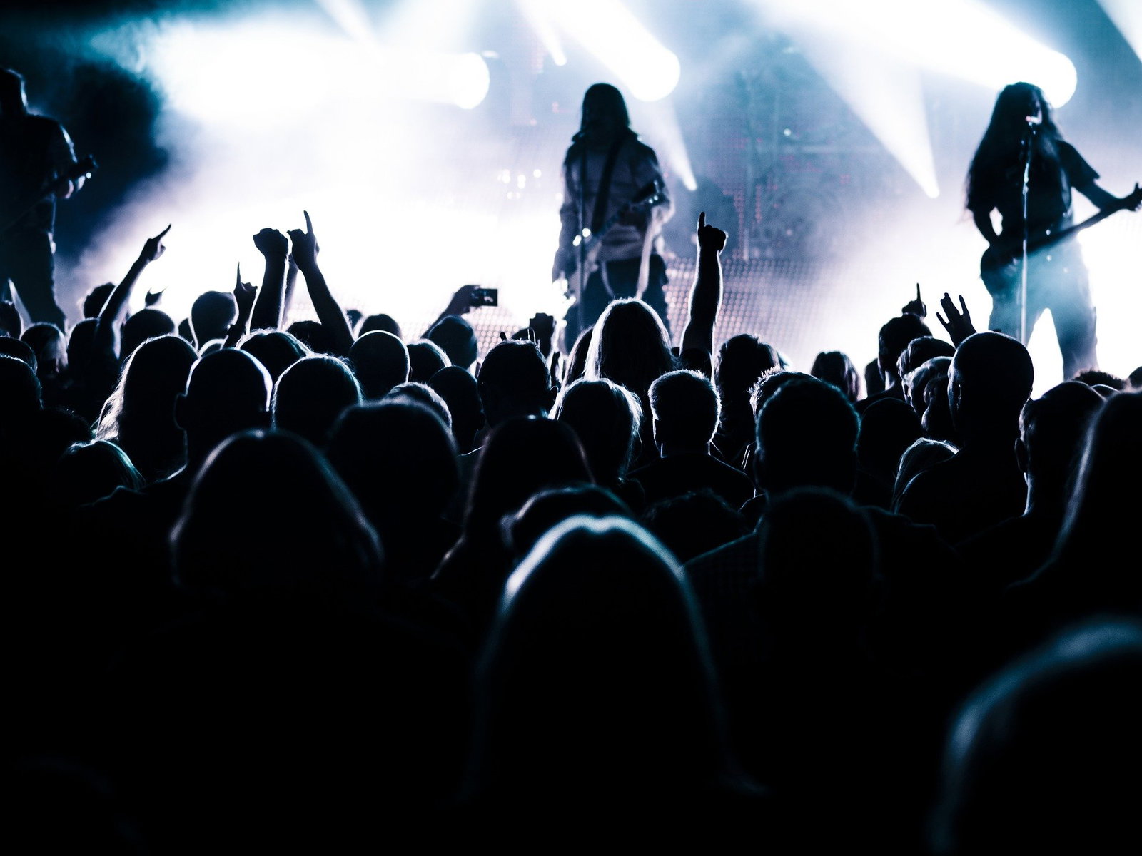 Zwei Personen spielen Musik für Fans. Die Bühne ist beleuchtet. Besucher recken Hände in die Luft.